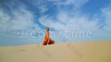 女人在沙丘上的沙漠中行走。 金发姑娘在烈日下的沙漠中的巴克汉散步，风吹乱了她的头发